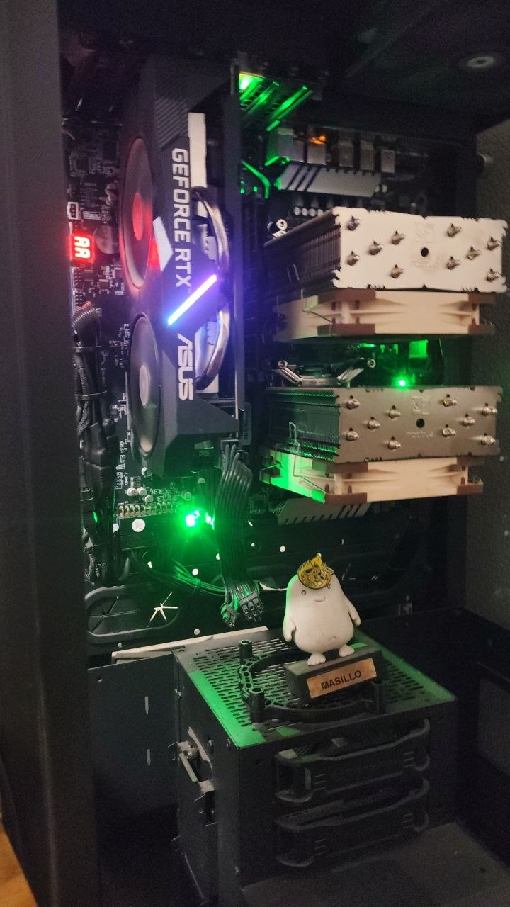 Interior de la torre: GPU, dos torres de refrigeración Noctua, LEDs verdes y una figurita con corona sobre la fuente